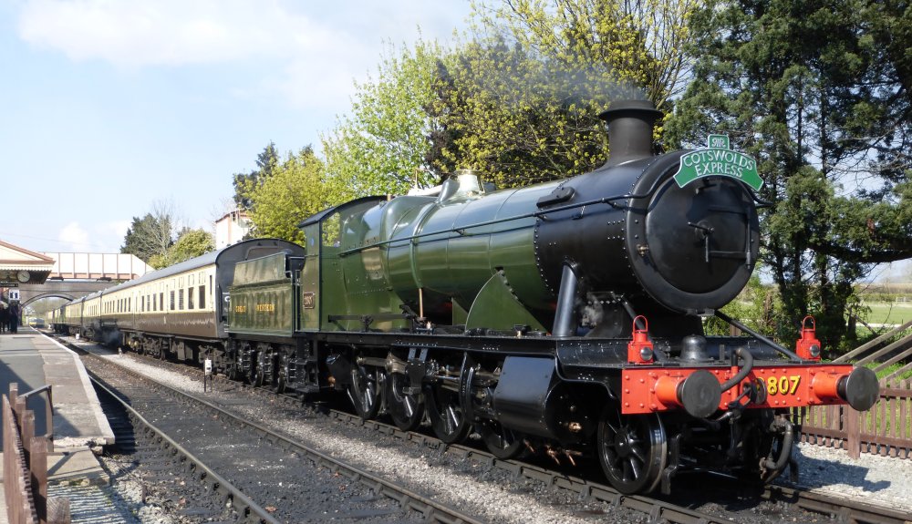 Ex GWR 2800 Class steam locomotive 2807 at Toddington station on the Gloucester and Warwickshire heritage steam railway, hauling a rake of the characteristic cream and brown liveried coaches of the Western Region, the headboard reads the COTSWOLD EXPRESS