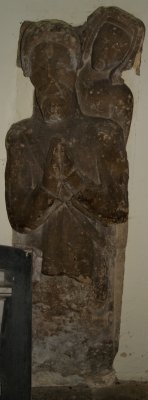 stone statue effigy of a praying knight dressed in mail armour with belt and sword, overlooked by a lady