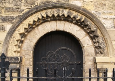 Another ornately carved Norman door arch and iron-work on the wooden door.