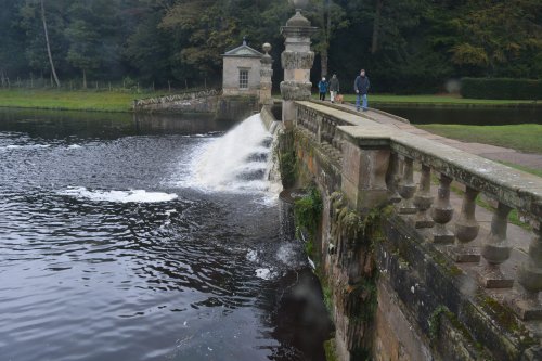 footbridge and weir connecting the fishing tabernacles Studley Royal walks park gardens in Autumn