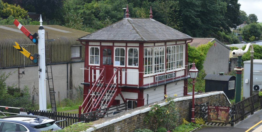 At Settle station, an old red and yellow semaphore signal, the disused, but preserved, signal box and the water column supply for thirst steam locomotives.
