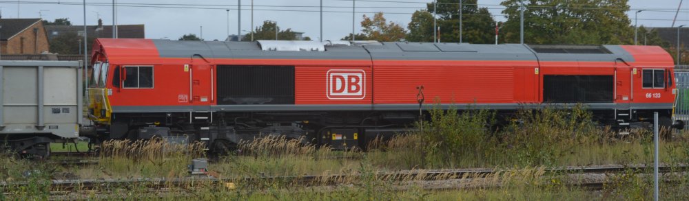 Red liveried DB Schenker Class 66 diesel locomotive 66133 with a south-east bound freight train at Peterborough station (2024)